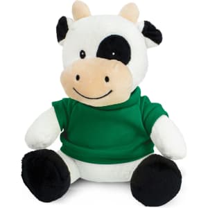 A plush cow toy with a white and black design, wearing a green shirt, seated with a smiling expression.