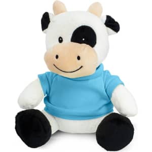 A plush cow toy with a black and white pattern, wearing a blue shirt, seated with a smiling expression.