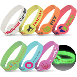 A variety of silicone wristbands in multiple colours, including green, pink, and orange, featuring logos and designs.