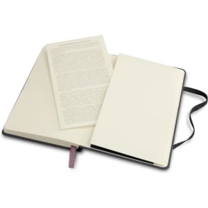 A Moleskine Classic hard cover notebook in black, featuring cream-coloured pages and a ribbon marker, opened to reveal a blank page.