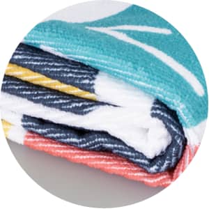 A folded beach towel featuring a vibrant design with teal, coral, and navy colours, displaying a logo.