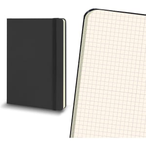 A large black Moleskine hard cover notebook featuring grid pages and an elastic band closure.