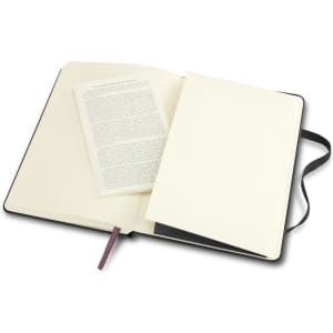 A large black Moleskine Classic Hard Cover Notebook, open to reveal cream pages and a blank insert.