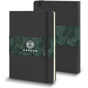A large, black Moleskine Classic Hard Cover Notebook with a green leaf-patterned band and an emblem.