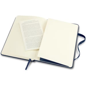 A navy hard cover medium notebook with blank pages and a ribbon bookmark, open to reveal an inner page.
