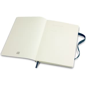 A large Moleskine classic soft cover notebook with a plain interior and a blue ribbon bookmark.