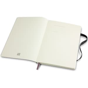 A large, soft-cover notebook in white with a black ribbon bookmark and an interior featuring blank pages. It has a logo.