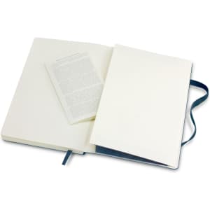 A large soft cover notebook in navy blue, featuring blank pages and a ribbon bookmark. Includes an insert.