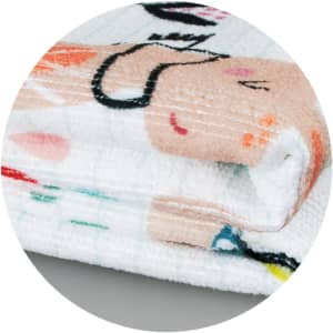 A folded Zen Yoga Towel featuring a playful design with soft pastel colours and a logo.