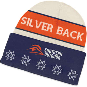 A knitted beanie in cream, orange, and navy with snowflake patterns and a logo.