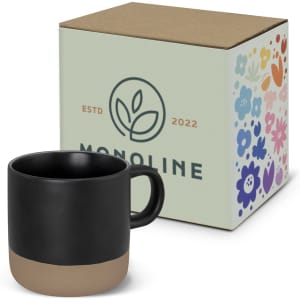 A coffee mug in black with a beige base, accompanied by a decorative box featuring a floral design and logo.