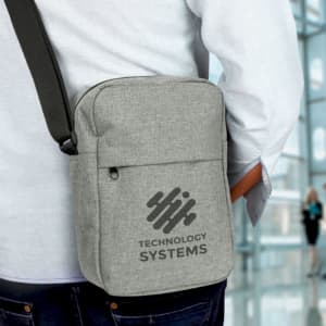 A grey travel bag with a shoulder strap and a logo, worn on a person's hip.
