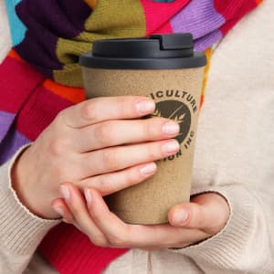 A drink bottle with a double wall design, featuring a beige exterior and a black lid, held by a person.