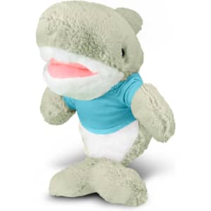 A plush shark toy in light green with a blue T-shirt and white belly, featuring a friendly smiling face.