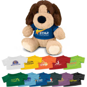 A plush dog toy with brown and cream fur, wearing a blue shirt with a logo, surrounded by various colourful t-shirts.