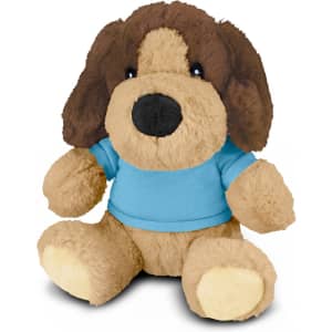 A plush dog toy with brown and tan fur, wearing a blue shirt, and a friendly expression. It has a branding logo.