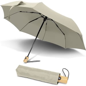 A compact umbrella in a soft green colour, displayed both open and folded, featuring a wooden handle and a logo.