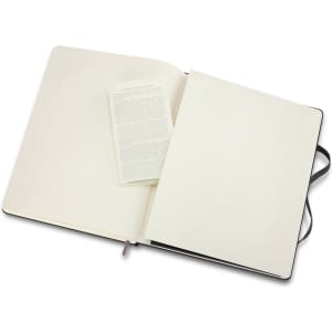 An extra-large Moleskine classic hard cover notebook in black, featuring plain cream pages and a ribbon bookmark.