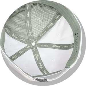 A white cap with a green underside features a mesh lining and has a logo inside.