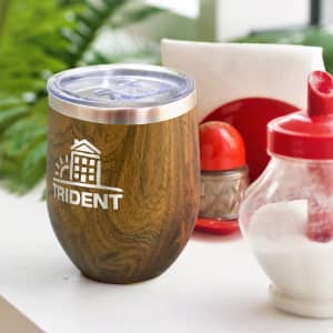 A drink bottle with a wooden finish and a silver lid, featuring a logo. Set against a background of condiments and greenery.