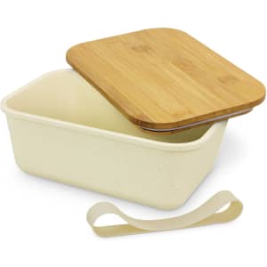 A cream-coloured lunch box with a bamboo lid and a silicone strap. The box has a smooth finish.