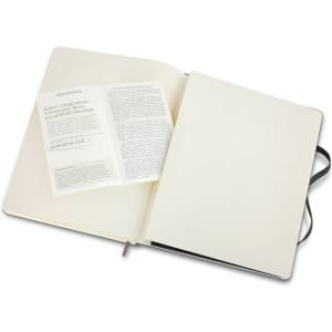 An extra large Moleskine soft cover notebook in black, open to reveal blank pages and a branded insert.