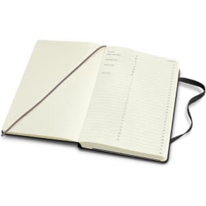 A large hard cover notebook with a black exterior and cream pages, featuring a ribbon bookmark and an inner pocket.