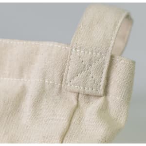 A close-up of a cream cotton shoulder tote bag, featuring a stitched handle with a cross-stitch detail.