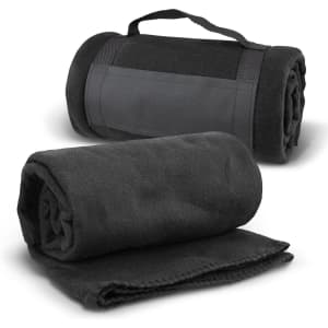 A rolled black fleece blanket with a strap lies beside an unrolled version, showcasing its soft texture.