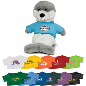 A grey and white seal plush toy wearing a blue t-shirt with a logo, alongside various t-shirts in different colours.