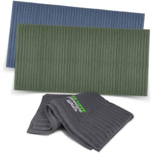 A set of three luxurious bath towels in shades of blue, green, and grey, featuring a logo on one towel.
