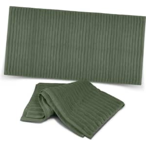 Two luxurious green bath towels with a ribbed texture, featuring a logo on one.