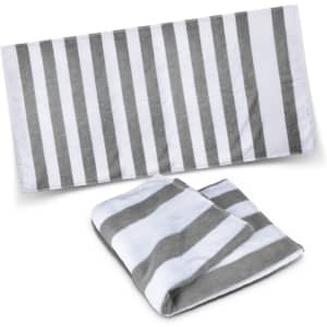 A striped beach towel in grey and white, displayed flat and folded, featuring a logo.