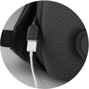 A close-up of a grey backpack featuring a USB port and a white charging cable connected.