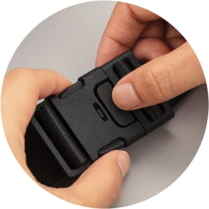 A hand pressing the release button on a black adjustable buckle, part of an Urban Belt Bag.