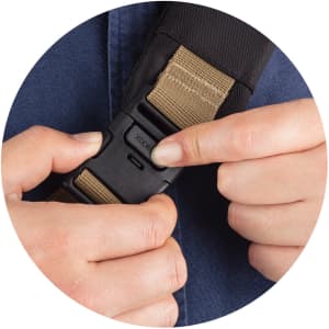 A hand adjusting a buckle on a strap, showcasing a dark fabric and a tan webbing. The image has a circular frame.
