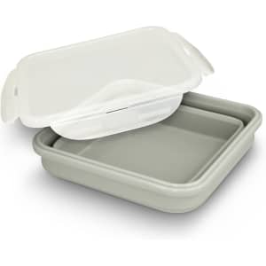A collapsible lunch box in white and grey with a lid. It has a simple design and features a logo on the side.