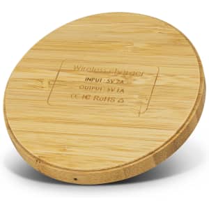 A round bamboo wireless charger with a smooth surface and a subtle engraved design. It has a natural finish and a logo.