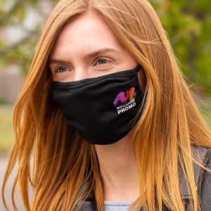 A black reusable 3-ply cotton face mask with a logo is worn by a person with long red hair outdoors.