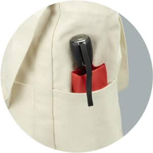 A cream canvas tote bag featuring a black handle and a red pocket holding a drink bottle. The bag has a logo.