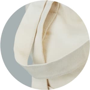 A cream canvas tote bag with sturdy straps, featuring a seamless design and soft texture.