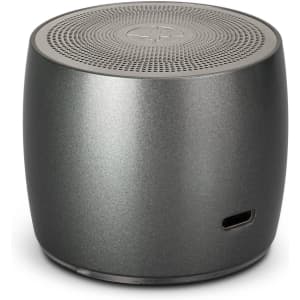 A round, grey speaker with a textured top and a logo, featuring a charging port on the side.