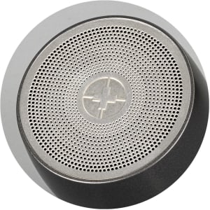 A silver and black portable speaker with a textured surface and a central logo.