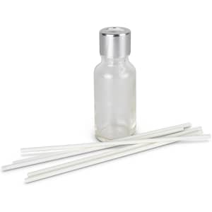 A glass scented diffuser bottle with a silver lid and five white reeds arranged beside it.
