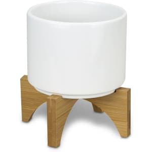 A white ceramic planter with a bamboo base, featuring a modern design and clean lines.