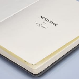 A black notebook with a cream-coloured interior and a branding logo on the inside cover.