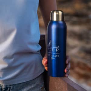 A drink bottle in metallic blue with a gold cap, featuring a logo and branding details.