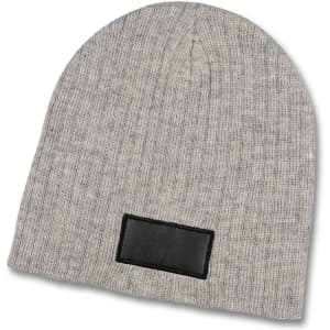 A grey cable knit beanie with a patch on the front, featuring ribbed texture and a rounded top.