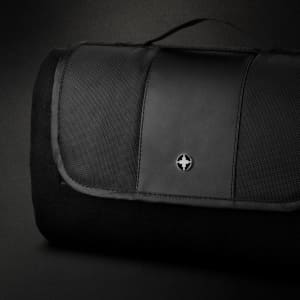 A black picnic blanket with a textured surface and a logo on the top, featuring a foldable design and carrying handle.