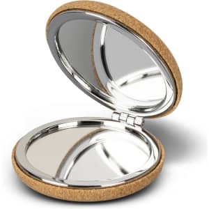 A compact mirror with a cork exterior and a shiny silver interior, featuring two reflective surfaces.